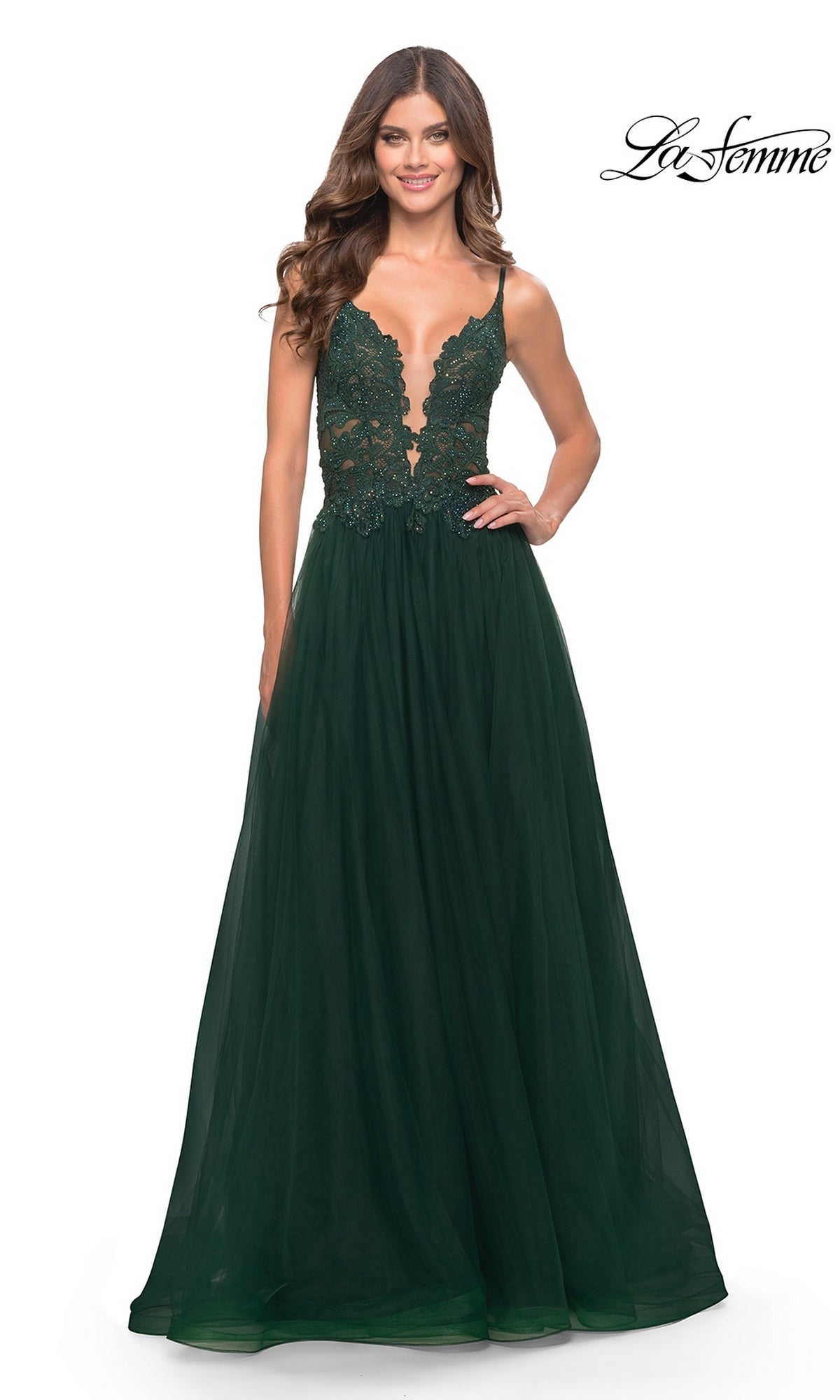A woman smiles in the Lace-Bodice Long Tulle Prom Dress: La Femme 31507, featuring a dark green lace bodice, flowing tulle skirt, and A-line silhouette. The La Femme logo appears in the top right corner.